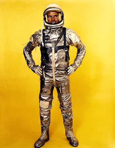 Vemos un traje de astronauta mas antiguo en color plateado con casco con careta de mica transparente con botas y guantes